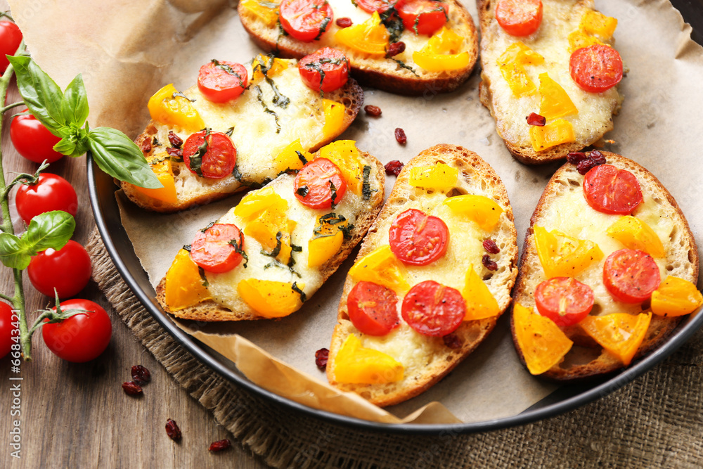 Tasty bruschetta with tomatoes on pan, on old wooden table