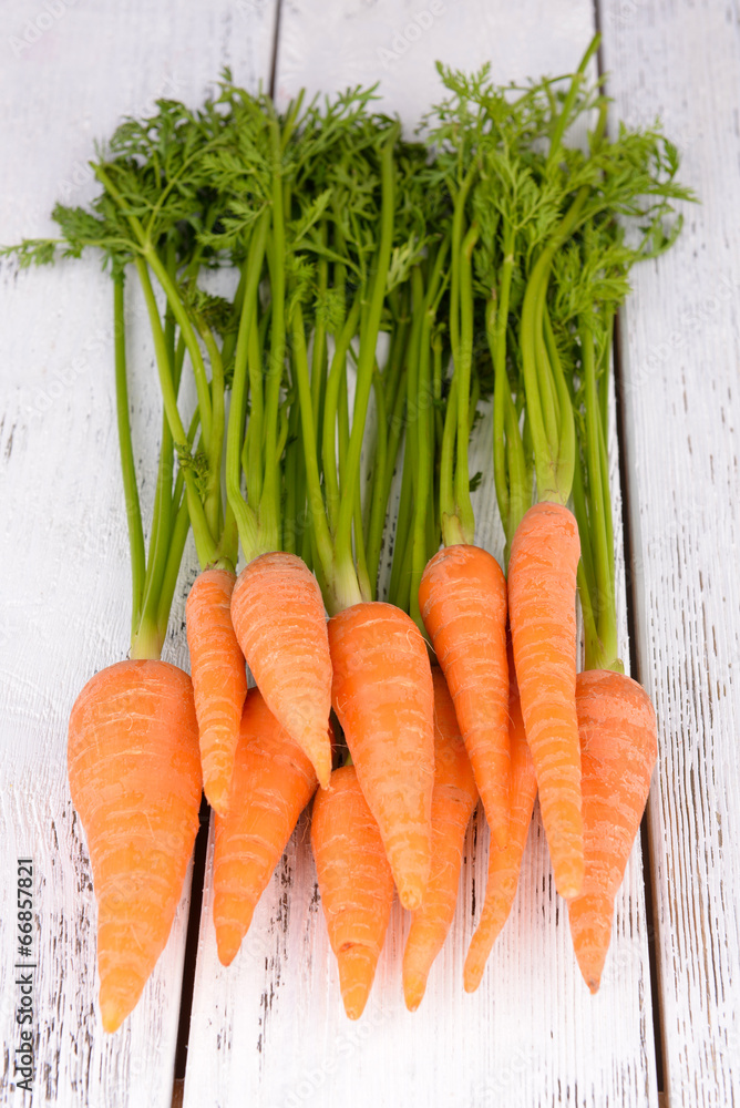 Fresh carrot with leaves on wooden background