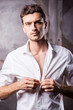 © gstockstudio - Handsome man buttoning shirt.