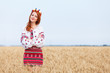Redhead girl in national ukrainian clothes on the wheat field.