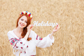 Wall Mural - Redhead girl in national ukrainian clothes with wooden word Holi