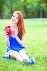 Poster - Redhead women with gift at green grass.