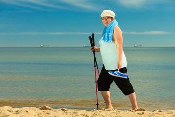 active woman senior nordic walking on a beach