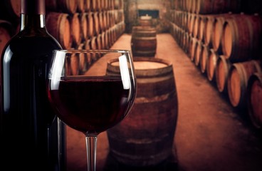 wine glass near bottle in old wine cellar with space for text