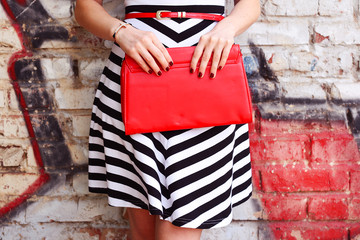 Fashionable woman with red handbag in hands closeup