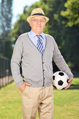 Canvas Print - Senior gentleman holding a soccer ball in a park