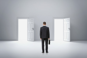 backview portrait of businessman in front of two doors