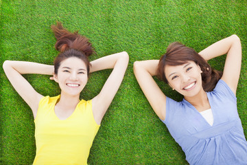 two happy young woman resting on grass