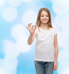 Wall Mural - little girl in white t-shirt showing ok gesture