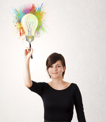 Young lady drawing a colorful light bulb with colorful splashes