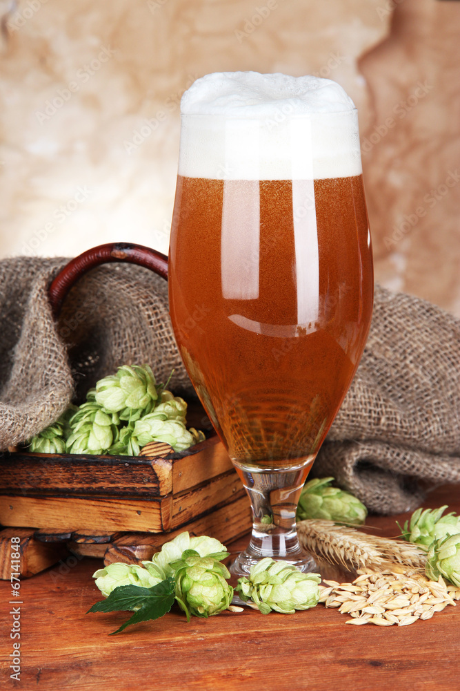 Glass of beer and hops, on wooden table