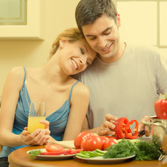 Wall Mural - Cheerful young cooking couple at home