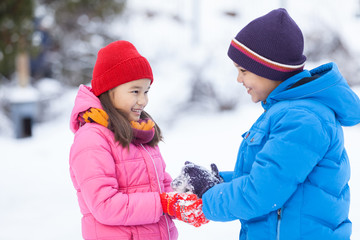 little boy helping small girl and smiling.