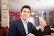 © Minerva Studio - Man holding a glass of white wine in a restaurant