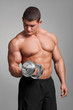 muscular man working out with dumbbells on gray background
