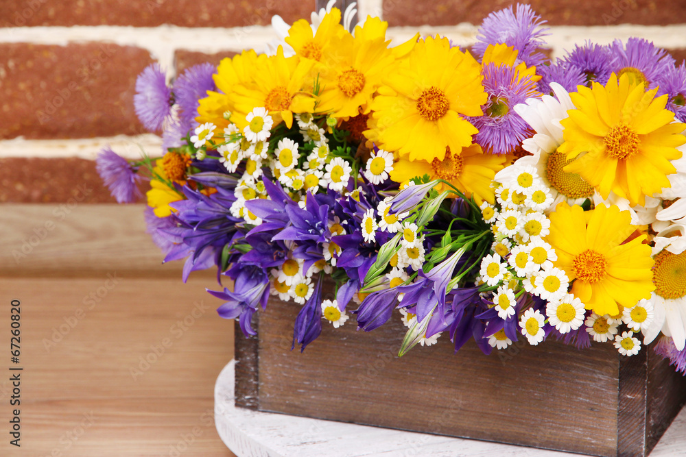 Beautiful flowers in crate on brick wall background