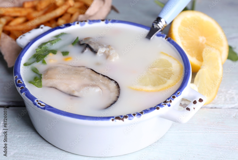 Tasty soup with oysters on wooden table