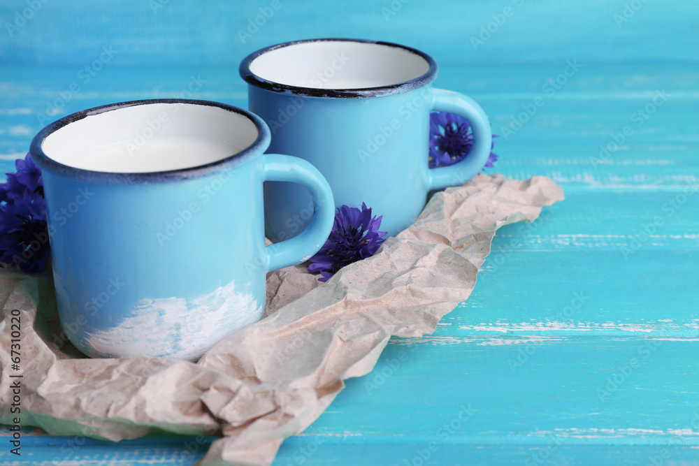 Cups of milk and cornflowers on wooden table