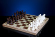 © Africa Studio - Chess board with chess pieces on dark color background