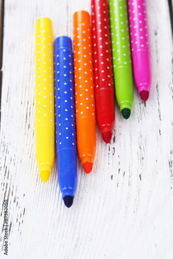 Bright markers on wooden table close-up