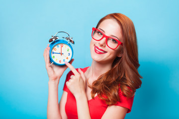 Wall Mural - Redhead girl with alarm clock on blue background.