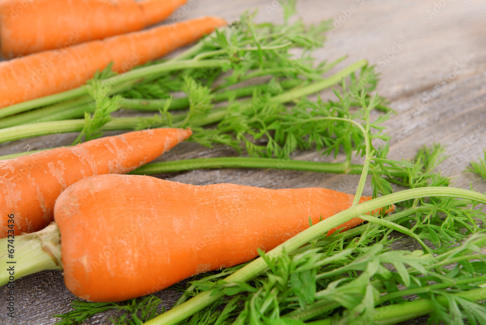 Fresh carrot with leaves on wooden background