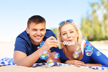 Wall Mural - Young couple blowing bubbles at the beach