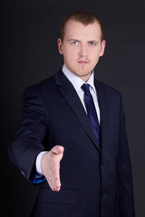 Wall Mural - business man with open hand ready to handshake over dark backgro