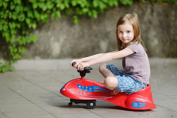 Wall Mural - Adorable little girl driving a toy car