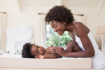 Happy mother with baby girl on changing table