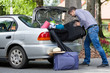 © Photographee.eu - Man trying to putting a travel bags into a car