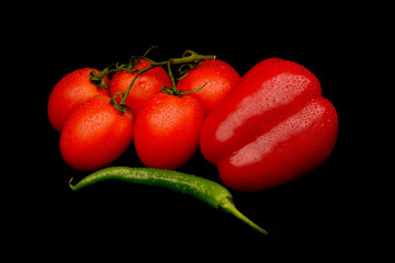 Frech tomatoes, green chilli and red capsicum on black backgroun