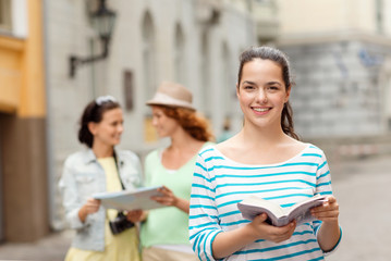 Wall Mural - smiling teenage girls with city guides and camera