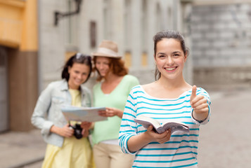 smiling teenage girls with city guide and camera