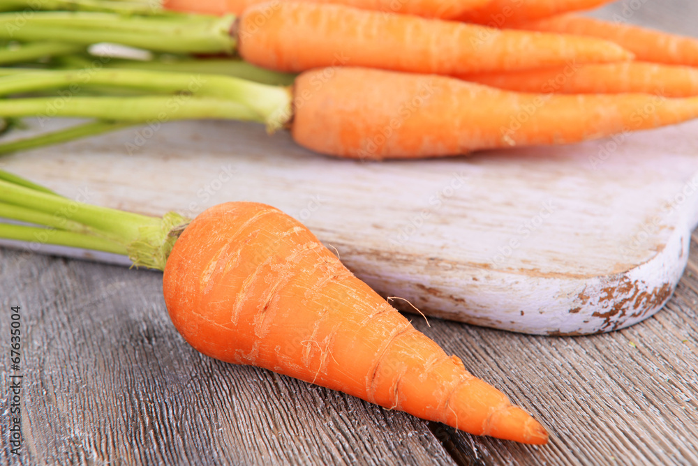 Fresh carrot on cutting board on wooden background