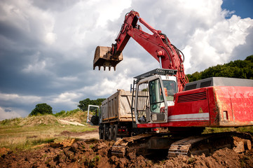 Wall Mural - Heavy bulldozer and excavator loading and moving red sand