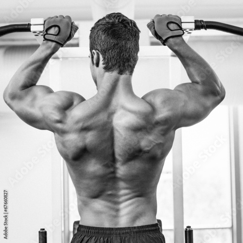 Naklejka dekoracyjna Male body builder doing pull ups at the gym