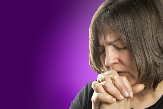 Mature woman in fervent prayer on violet background