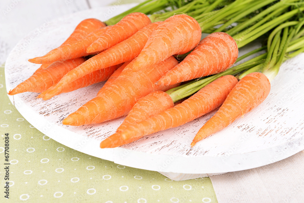 Fresh carrot on wooden stand on table close up