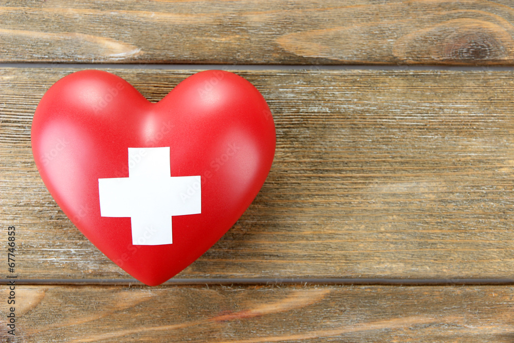Red heart with cross sign on wooden background