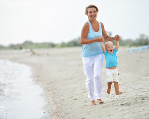 Wall Mural - Smiling young mother with little child running.