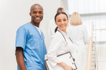 Wall Mural - Two cheerful doctors looking over shoulder and smiling while the