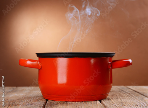 Fotografie, Obraz Cooking pot with steam on table on brown background
