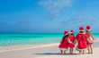 © travnikovstudio - Happy family of four on beach in red Santa hats