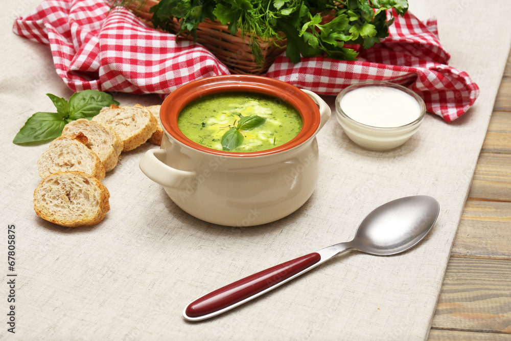 Tasty soup in saucepan on tablecloth, close up