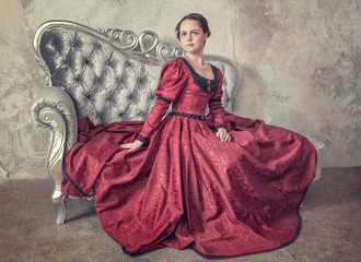 Beautiful woman in medieval dress on the sofa