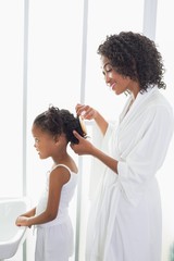 Pretty mother brushing her daughters hair