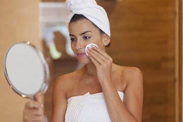 Woman cleaning face in bathroom