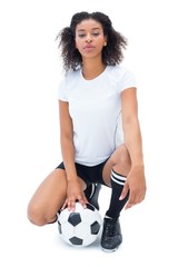Wall Mural - Pretty football player in white holding ball looking at camera