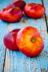 Wall Mural - fresh organic flat nectarines on an old wooden background